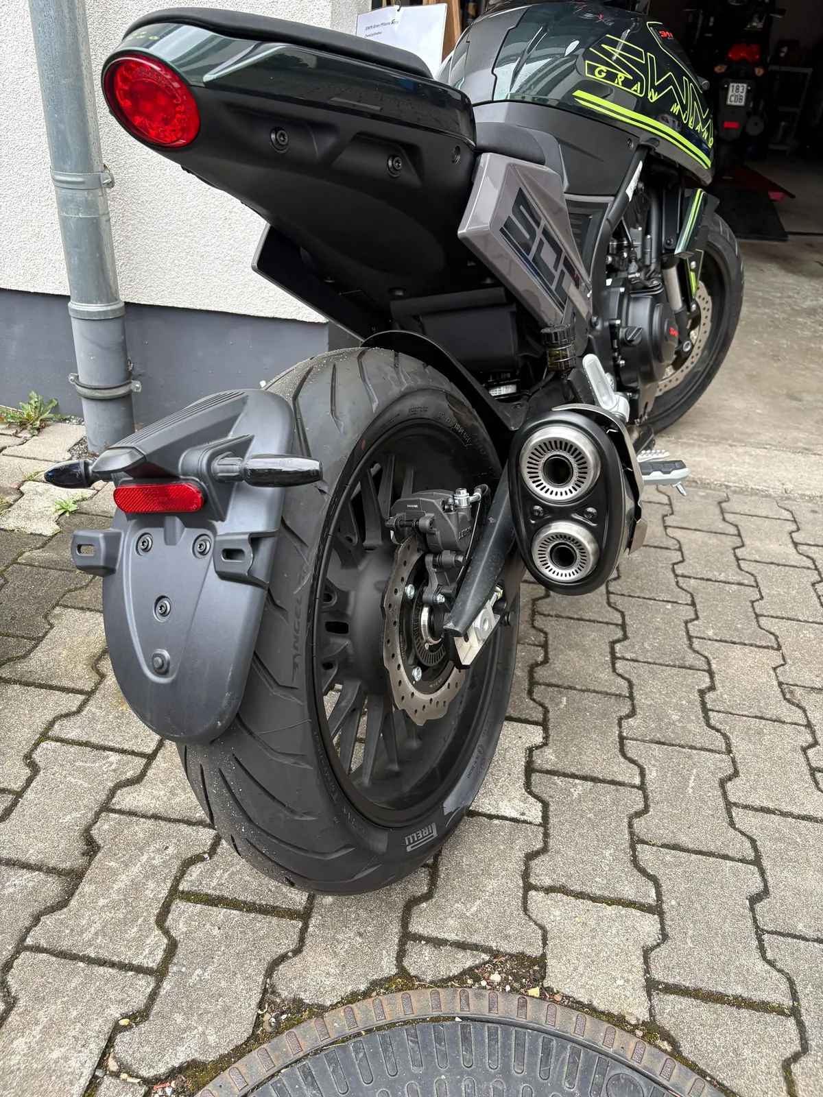 Heck eines Motorrads mit Doppelauspuff auf dem Pflaster