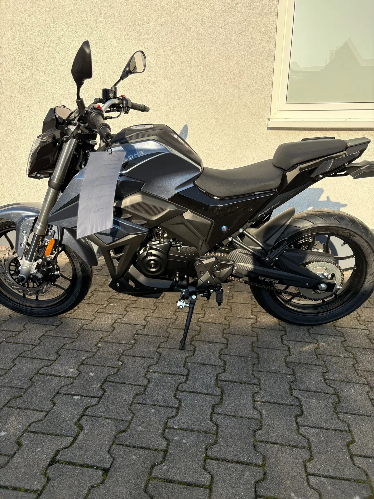 Blau-schwarzes Naked Bike mit Preisschild auf dem Hof der Werkstatt Horniroller