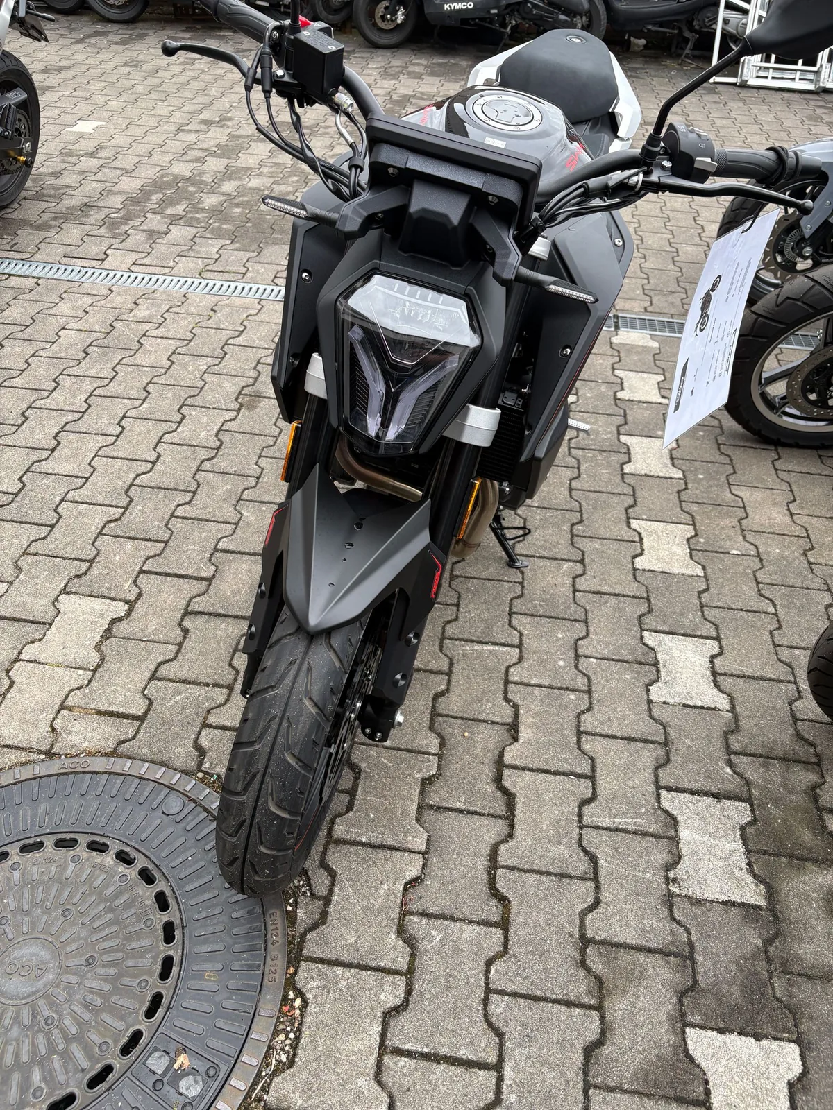 Graues Naked Bike von vorn auf dem Hof der Werkstatt