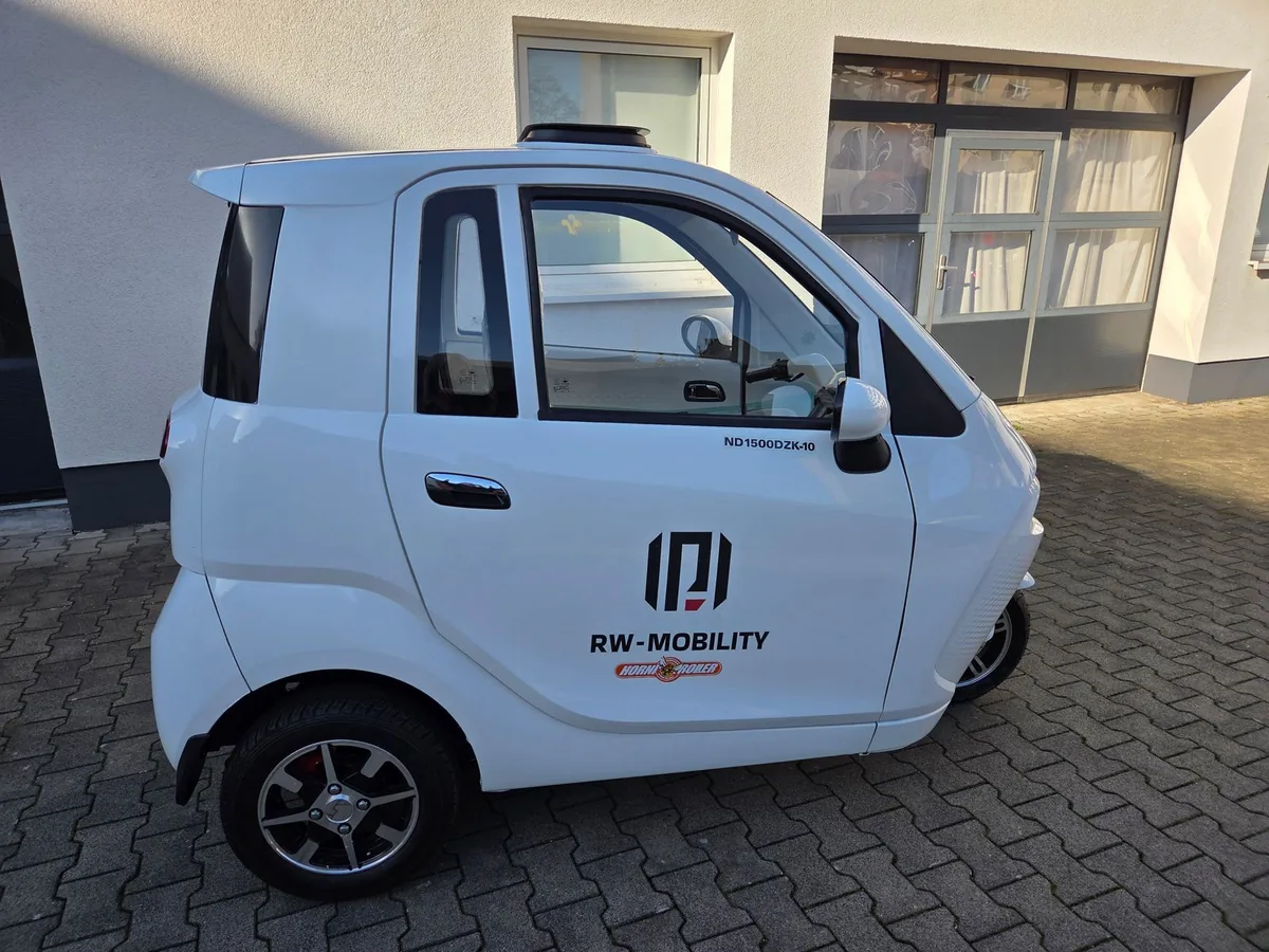 Weißes Kleinfahrzeug von RW-Mobility vor dem Werkstattgebäude